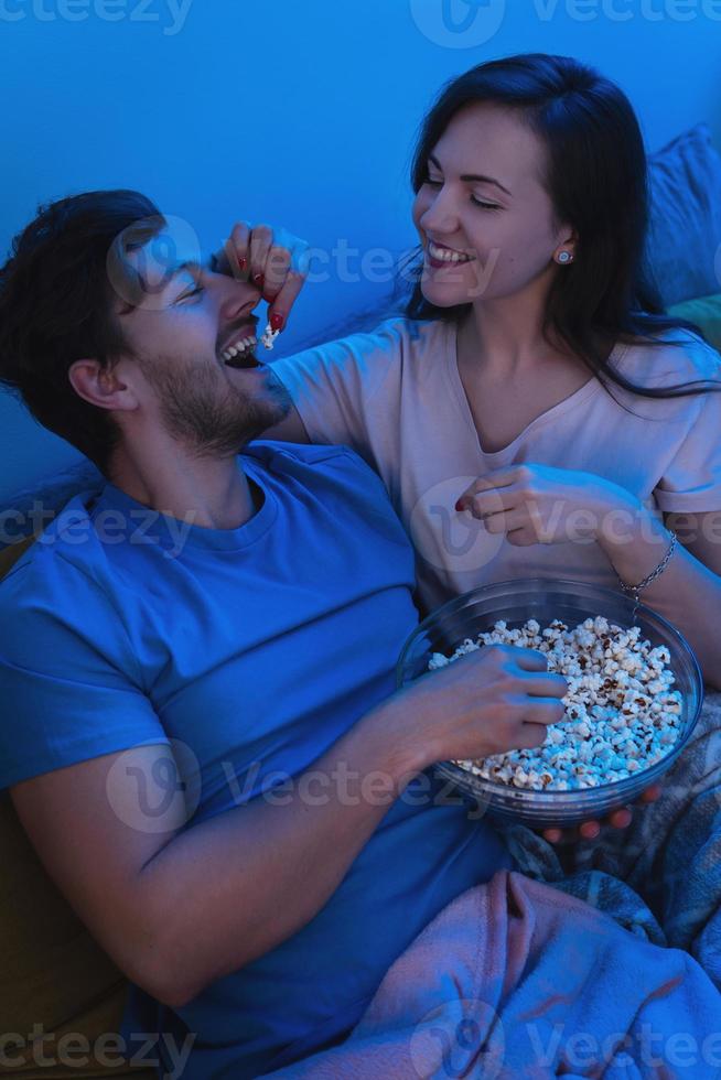 giovane e contento coppia mangiare Popcorn e Guardando film foto