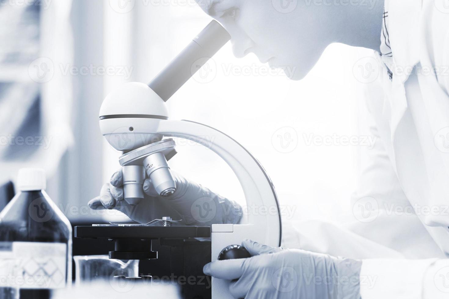 donna scienziato è utilizzando microscopio nel un' laboratorio durante ricerca foto