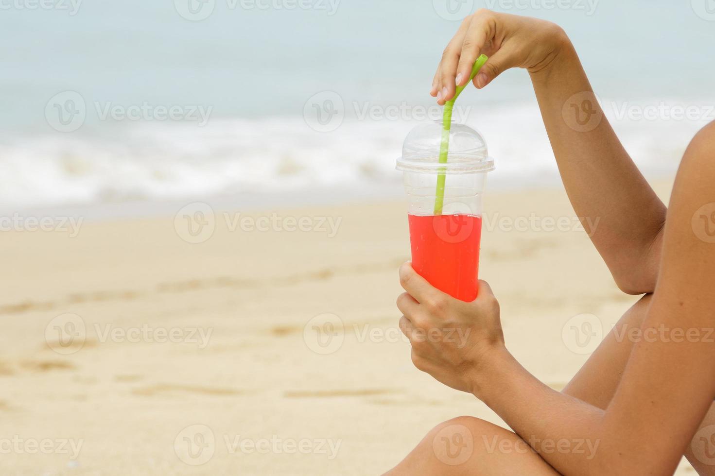 donna con un' rosso rinfrescante bevanda su il spiaggia foto