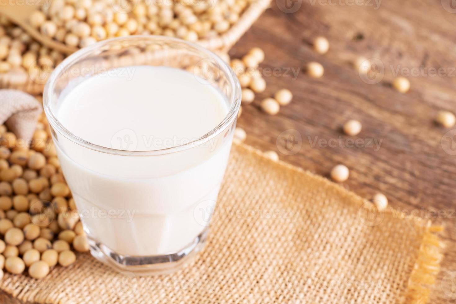 soia latte nel un' bicchiere con semi di soia su un' di legno tavolo biologico colazione, alto proteina, sano, agricolo prodotti, vegetariano foto