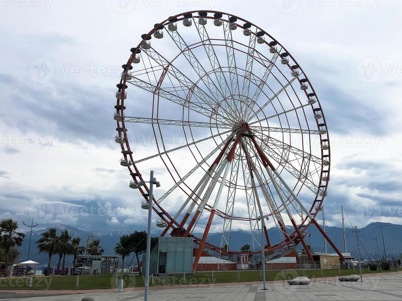 un' grande il giro bellissimo Ferris ruota, un' panoramico piattaforma nel un' parco su un' tropicale mare caldo estate ricorrere con palma alberi contro un' blu cielo foto