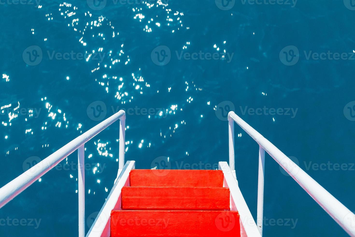 il rosso scala con bianca ringhiere va in il azzurro chiaro acque di il nero mare foto