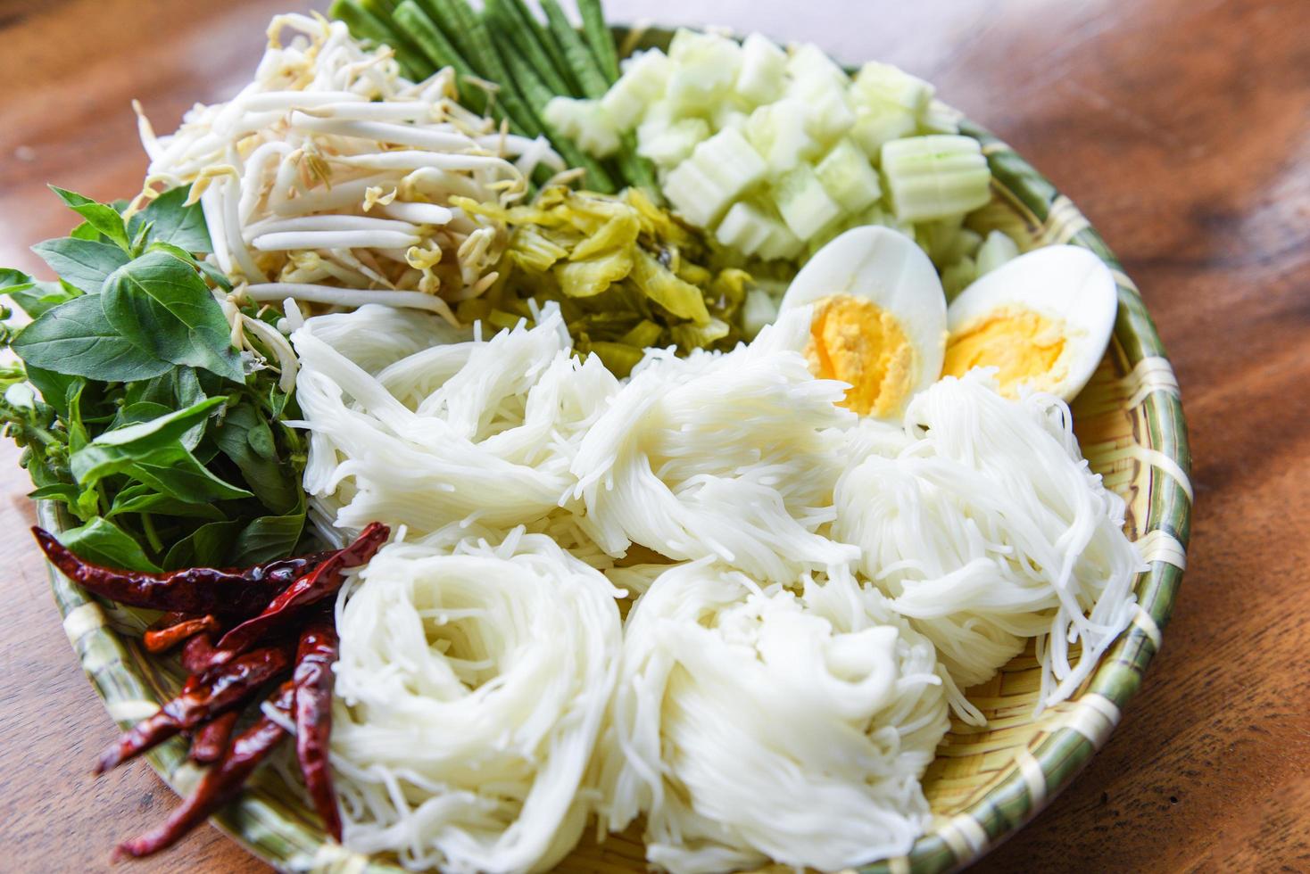 cibo thailandese vermicelli noodle uova sode e verdure fresche su piatto servito su un tavolo di legno - spaghetti di riso tailandesi foto