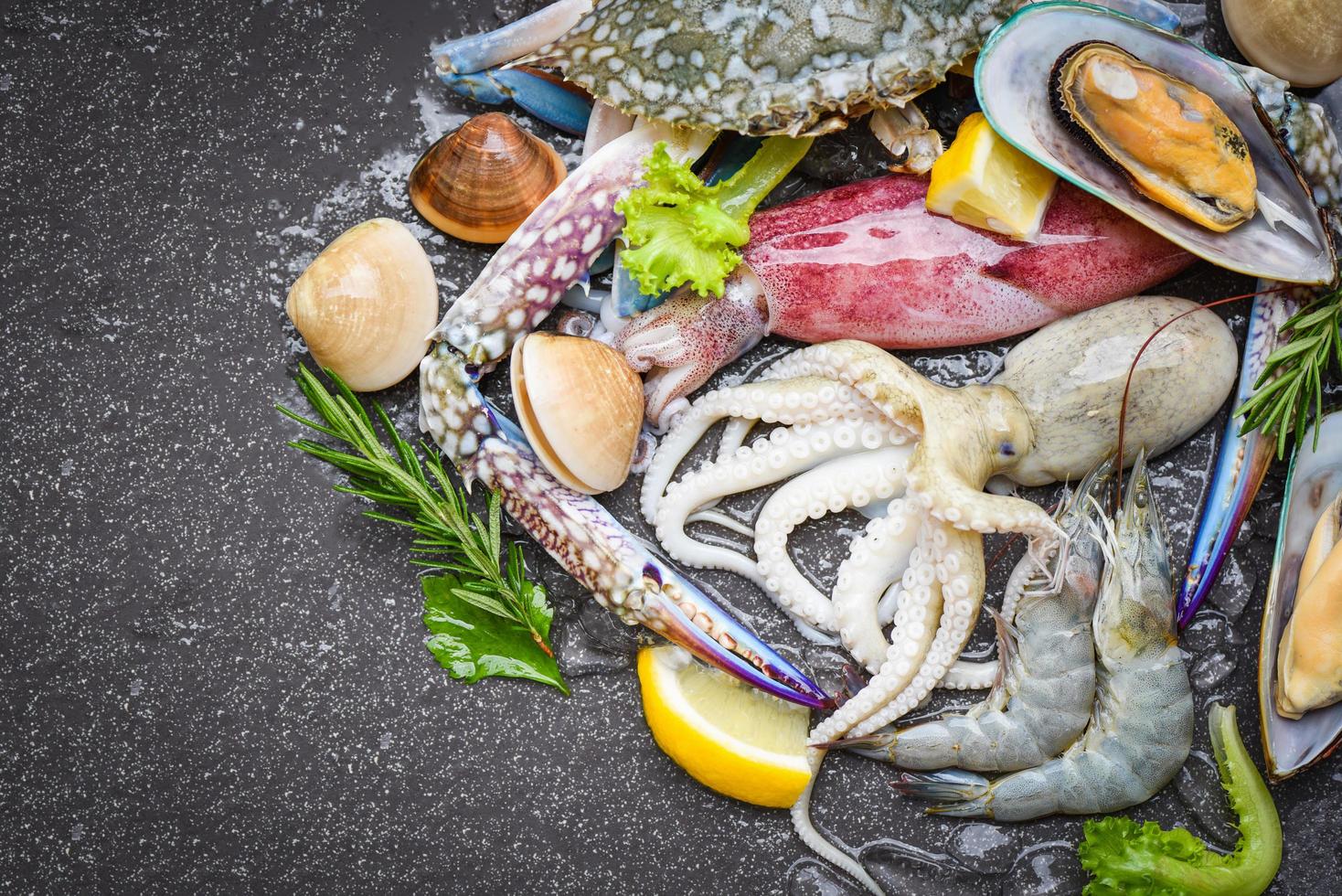 buffet di pesce crudo fresco con limone rosmarino ingredienti erbe e spezie - frutti di mare crostacei su ghiaccio congelati con gamberi gamberi chele di granchio conchiglia vongole veraci calamari polpi e cozze al ristorante foto