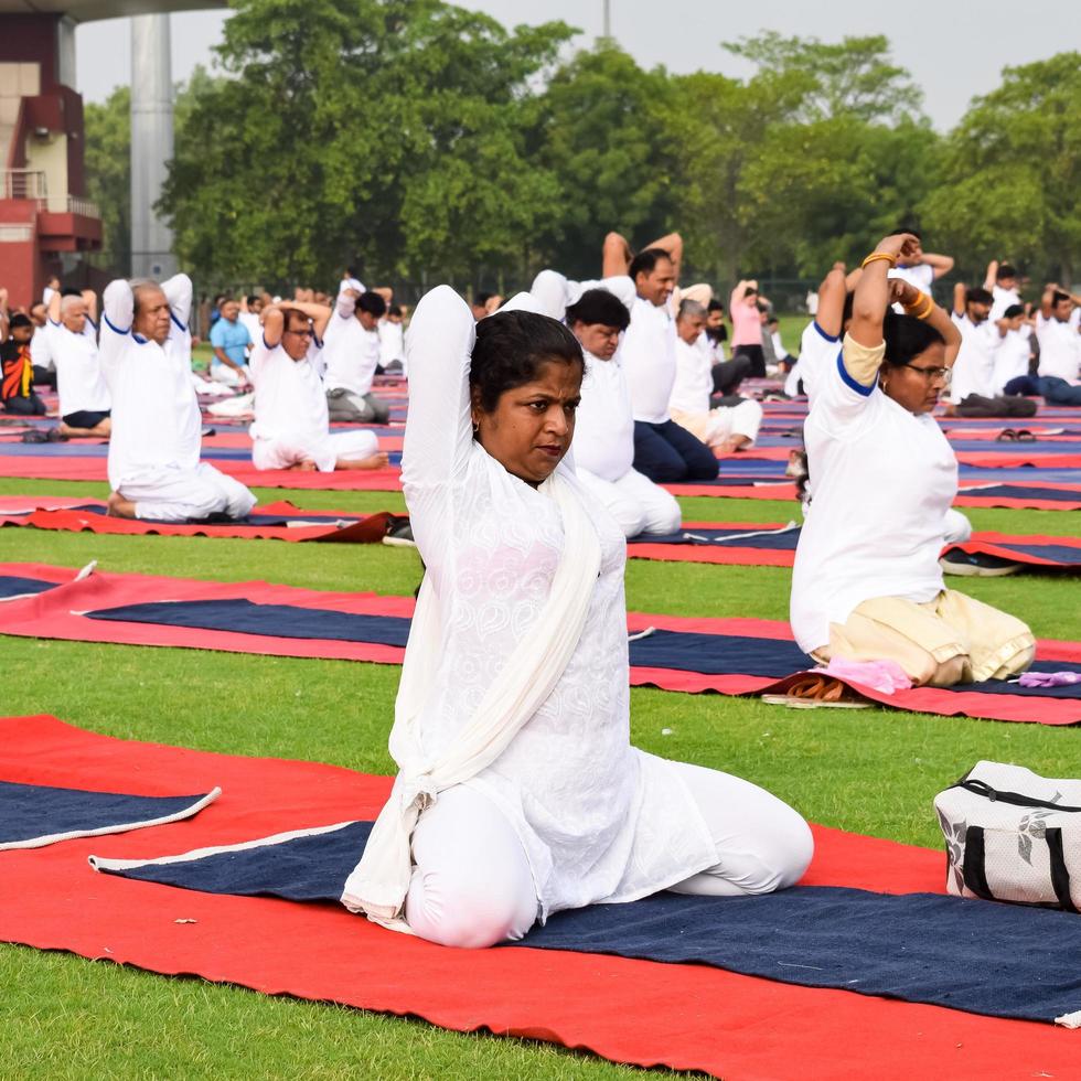 nuovo delhi, India, giugno 21 2022 - gruppo yoga esercizio sessione per persone a yamuna gli sport complesso nel delhi su internazionale yoga giorno, grande gruppo di adulti frequentando yoga classe nel cricket stadio foto