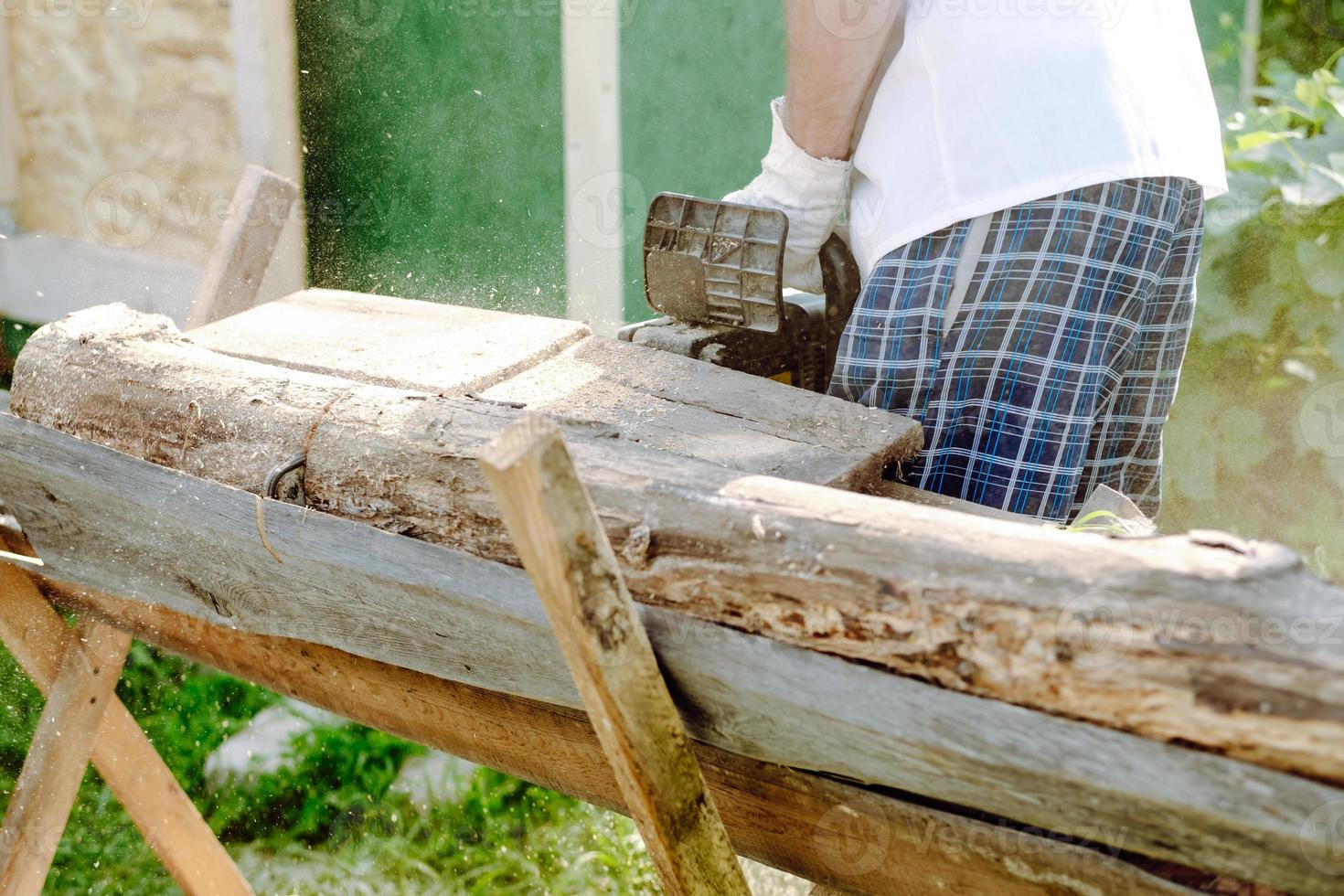 motosega nel il mani di un' lavoratore taglio legna da ardere, avvicinamento foto