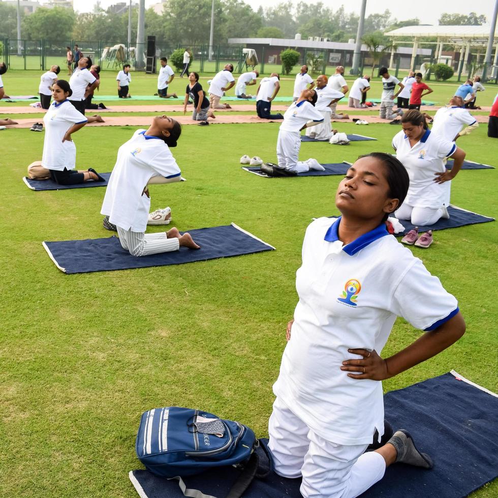 nuovo delhi, India, giugno 21 2022 - gruppo yoga esercizio sessione per persone a yamuna gli sport complesso nel delhi su internazionale yoga giorno, grande gruppo di adulti frequentando yoga classe nel cricket stadio foto