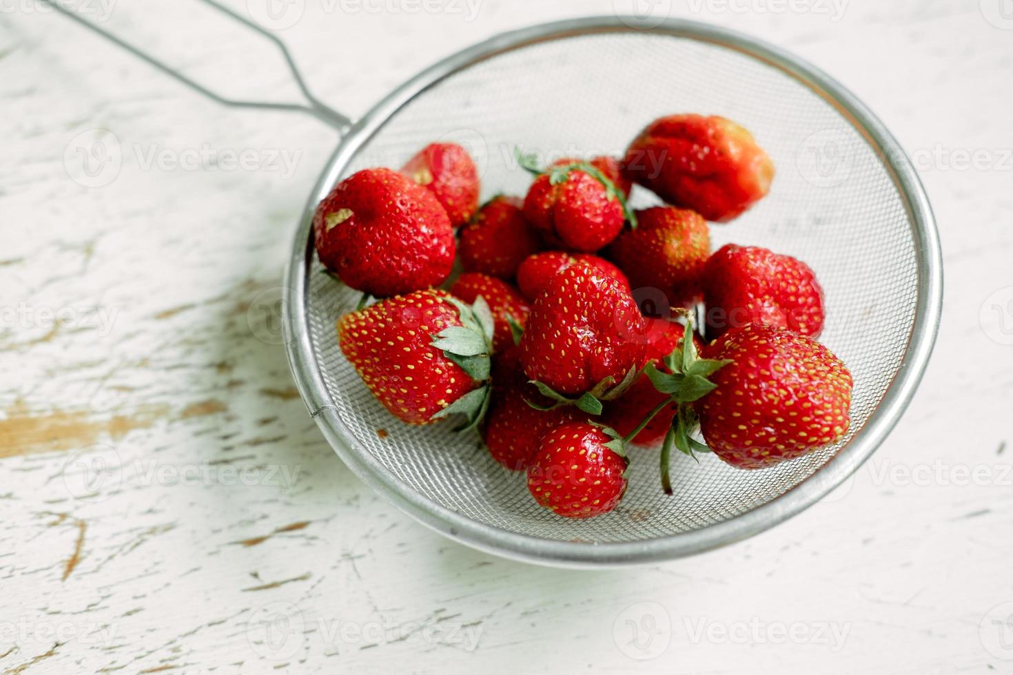 luminosa dolce e succoso fragole . rosso fragole nel un ferro colino. gocce di acqua su fresco frutti di bosco foto