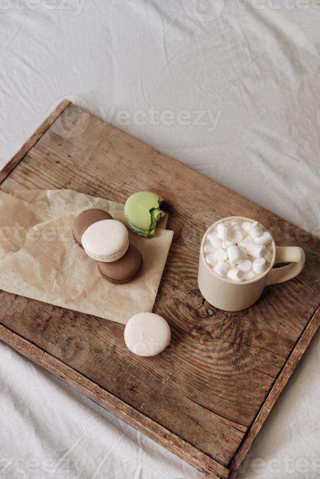 caffè con marshmallows e amaretti su un' di legno vassoio, nel letto. esteticamente bellissimo telaio. dolci nel letto. caldo cioccolato con marshmallows. accogliente e caldo giorno nel letto foto