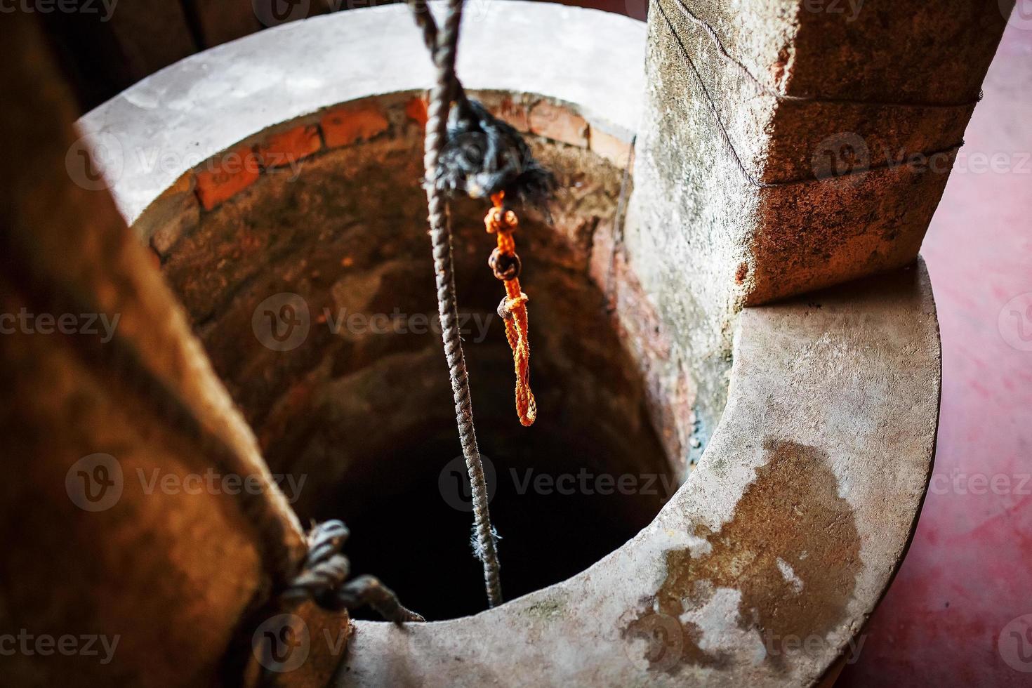 antico pietra il giro bene con potabile acqua e un arancia corda. foto