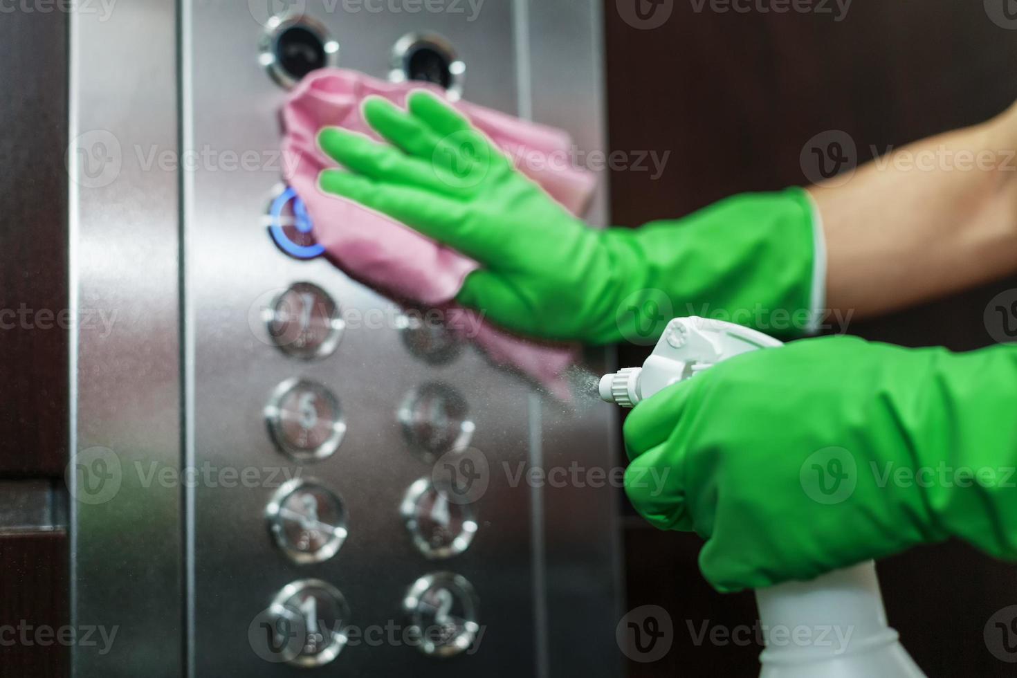 disinfezione e igienico cura utilizzando alcool spray su il ascensore pulsante. foto