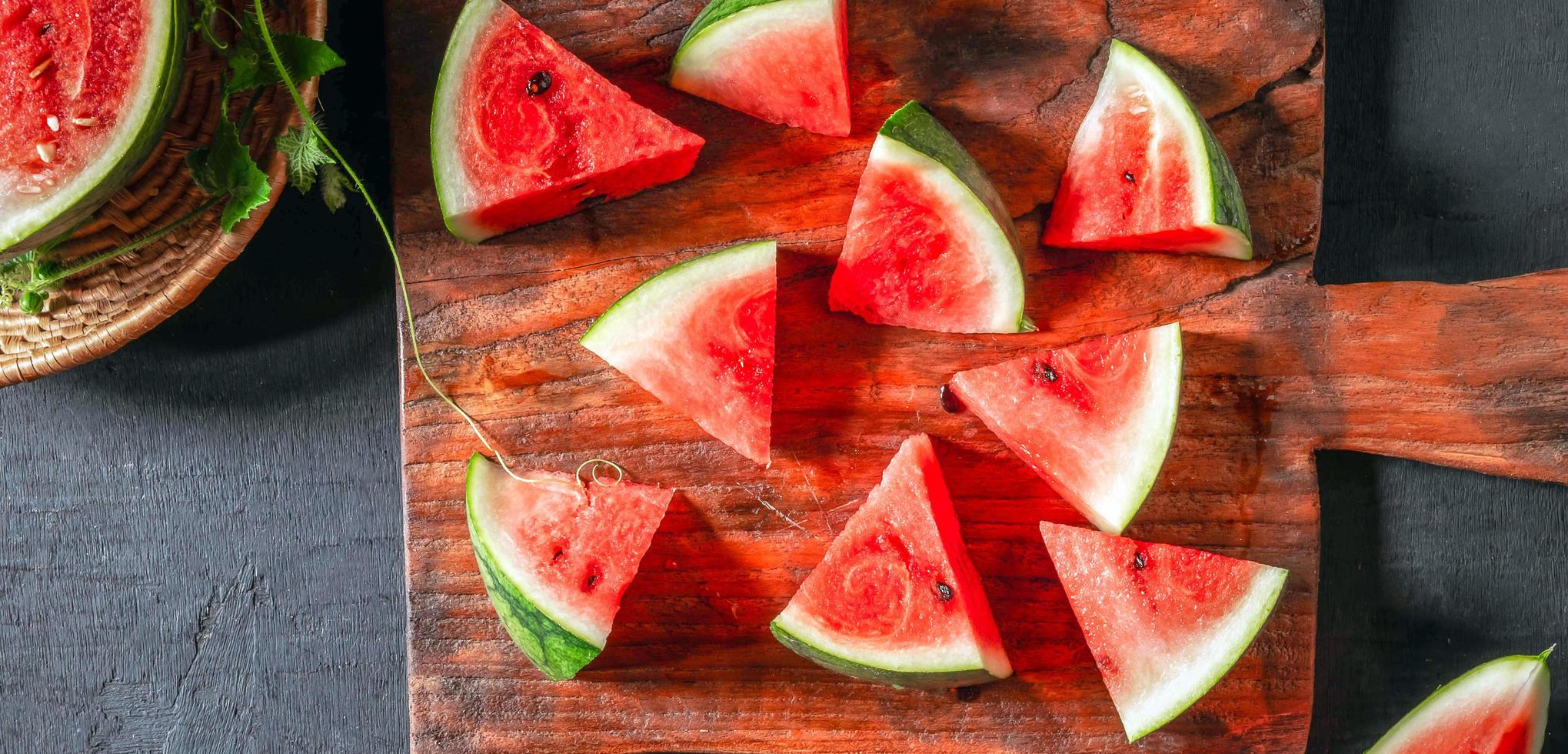 fresco anguria frutta tagliare in pezzi su un' di legno taglio asse, il anguria frutta era tagliare nel metà, rivelatrice suo luminosa rosso carne. foto