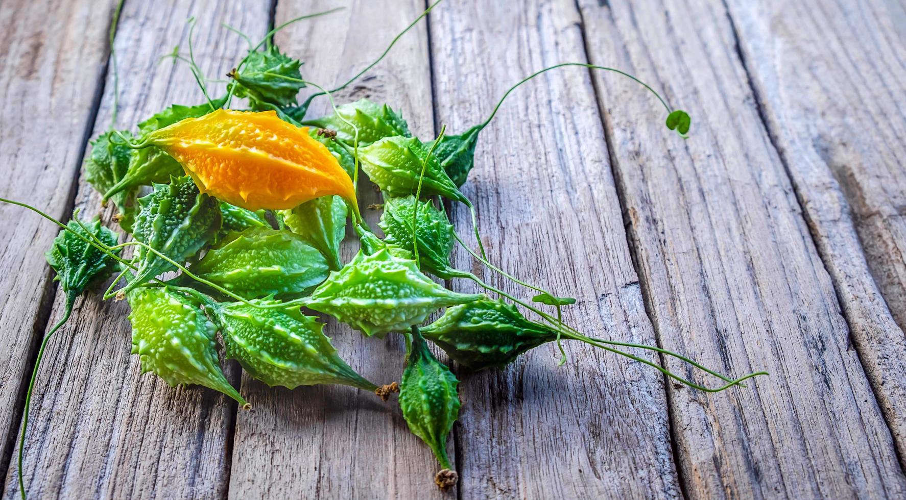 vicino su piccolo amaro melone anche conosciuto come amaro zucca, cetriolo, o momordica charantia su vecchio di legno foto