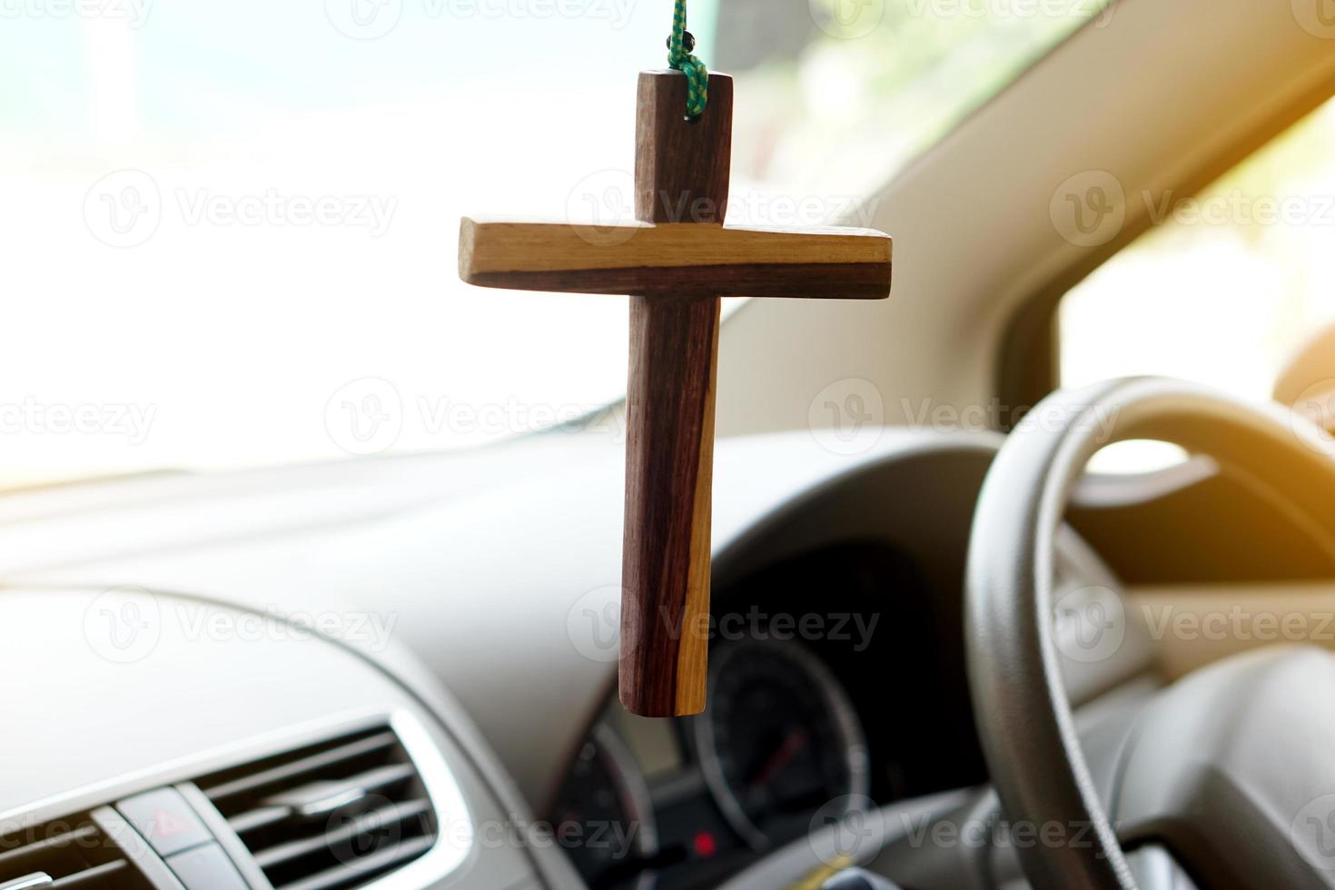 avvicinamento di legno crocifisso appendere nel davanti timone ruota e consolle di il macchina. concetto, talismano, amuleto per impedire incidenti. credenza, fede, santo nel Dio per proteggere quando guida. foto