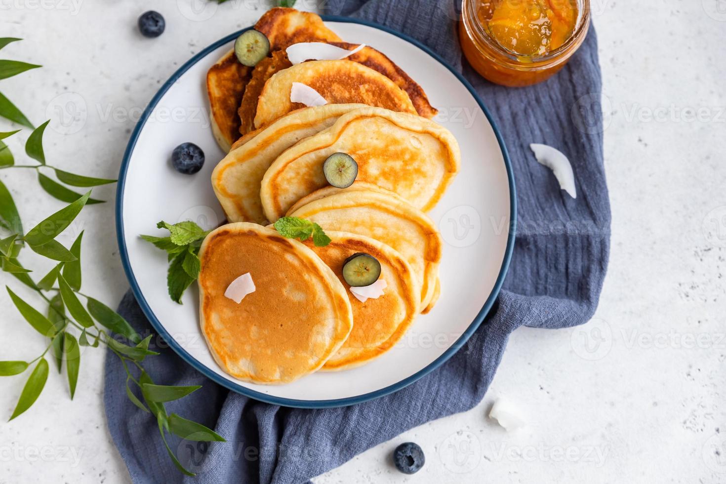 tradizionale soffice Pancakes con arancia marmellata, mirtilli, Noce di cocco patatine fritte e menta per salutare colazione, leggero sfondo. alto chiave fotografia. foto