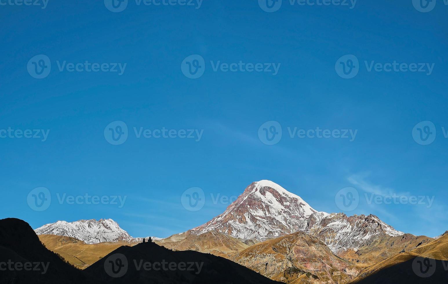 caucasico alto gamma, il superiore di montare kazbek illuminato di il crescente sole, presto autunno. Georgia viaggio e turismo, il trekking nel il montagne foto