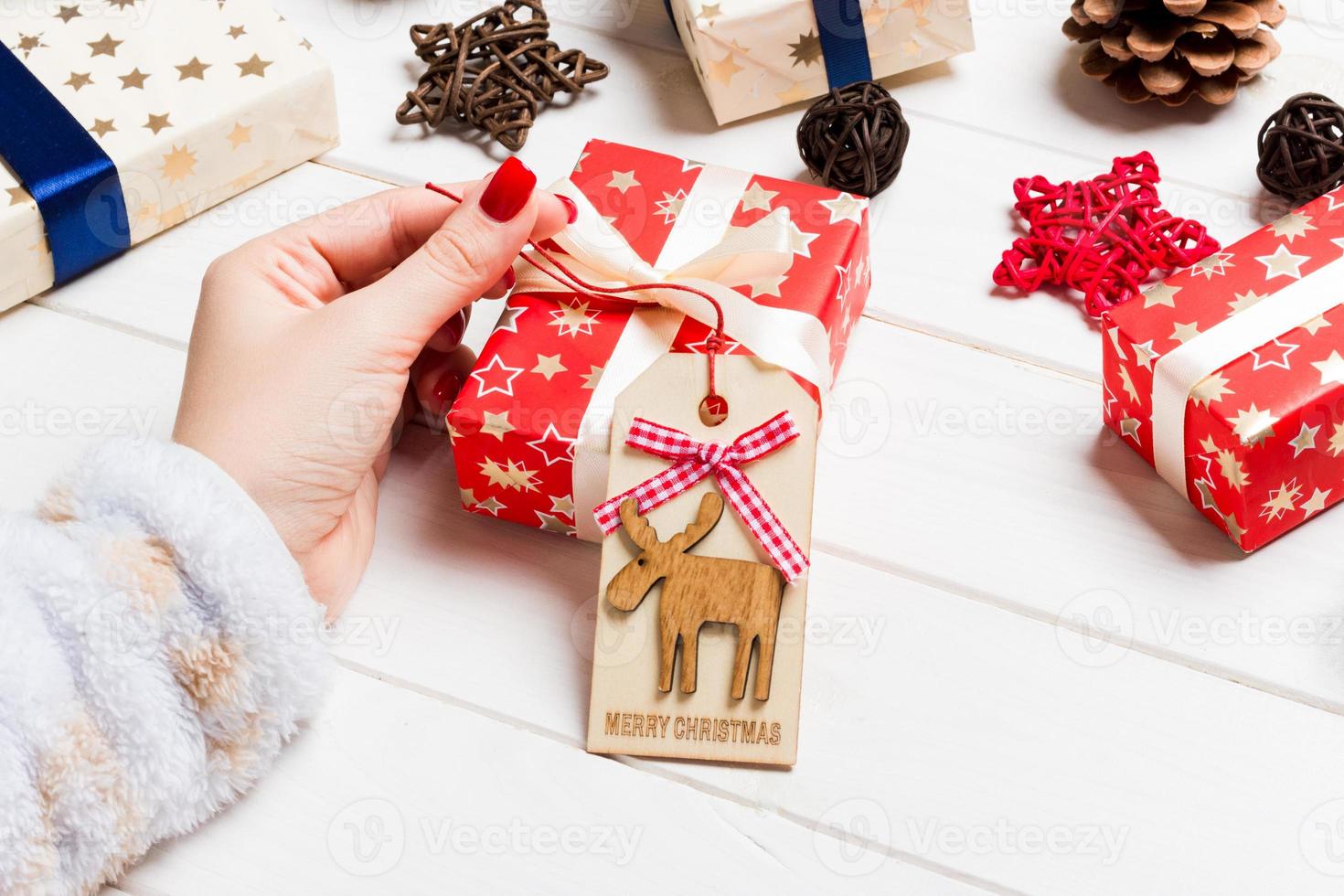 superiore Visualizza di femmina mano cravatta su nuovo anno presente su festivo di legno sfondo. Natale tempo concetto foto