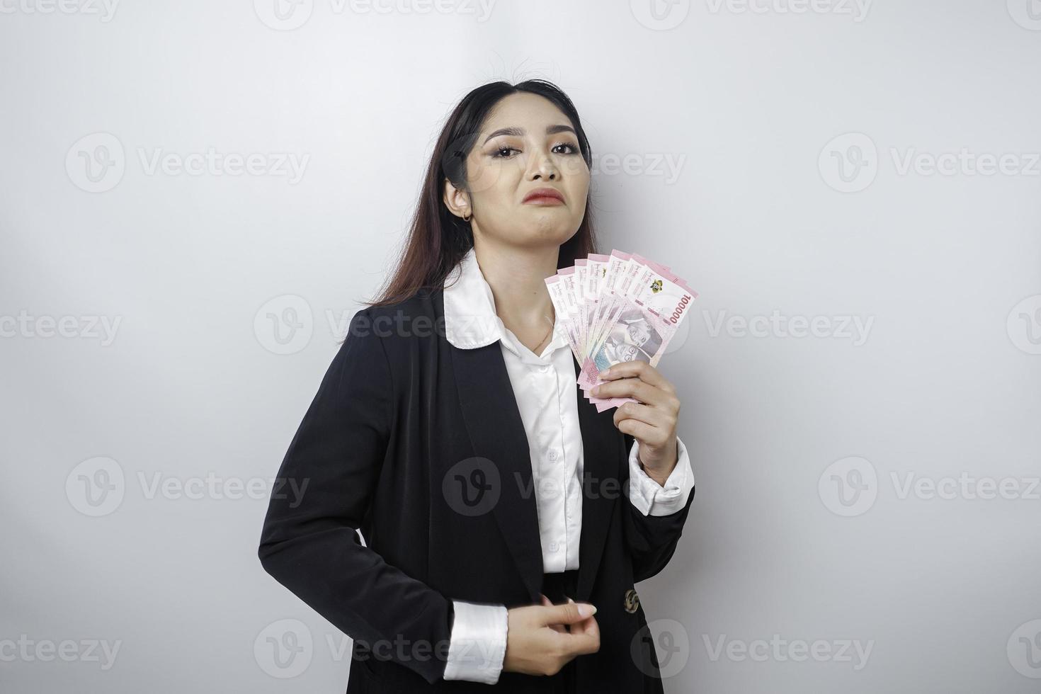 un' ritratto Se un' giovane donna d'affari con un' pila di i soldi nel indonesiano rupia nel sua mani isolato di bianca sfondo foto