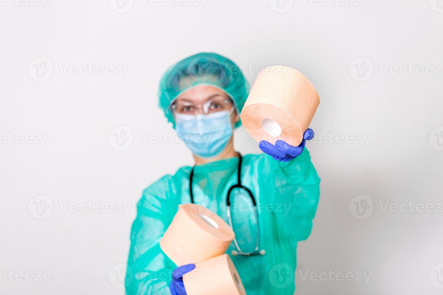 medico indossare ppe protezione suite o infermiera con un' stetoscopio detiene un' rotoli di gabinetto carta. mancanza di gabinetto carta nel il quarantena di coronavirus, il concetto di un' carenza di cose nel I negozi foto
