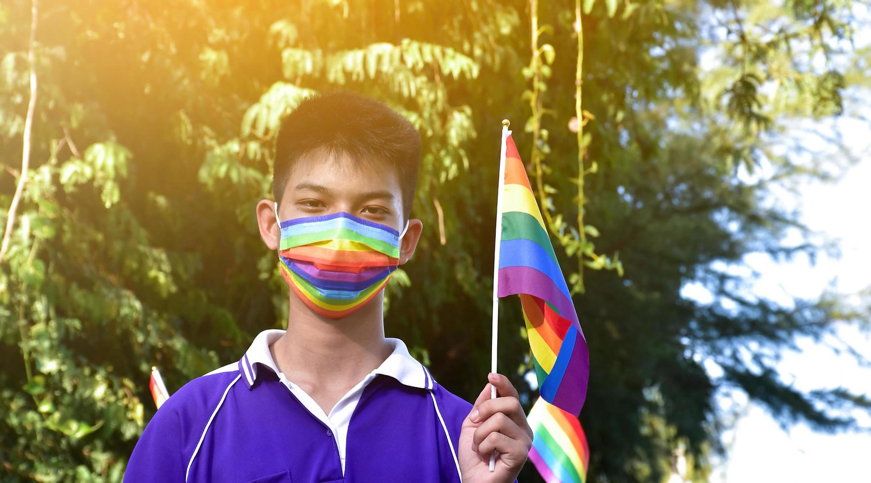 ritratto asiatico giovane ragazzo detiene arcobaleno bandiera, lgbt simbolo, nel mani mentre unendo il suo lgbt attività a scuola, concetto per lgbt Comunità celebrazione nel orgoglio mese, giugno, 2023, in giro il mondo. foto
