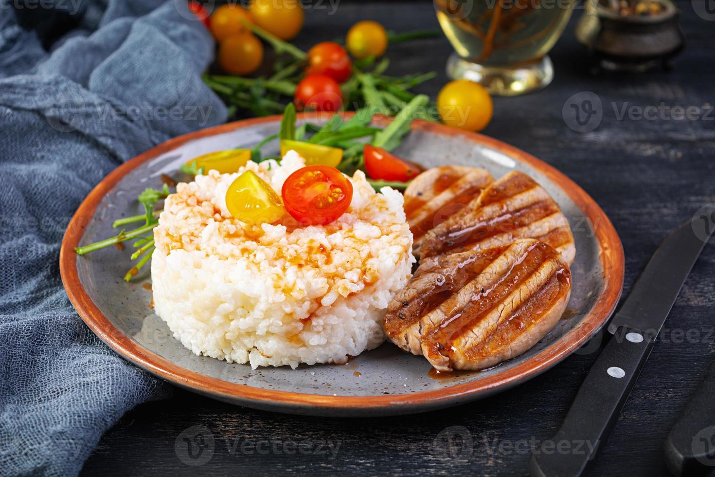 riso con grigliato Maiale carne, pomodori e verde erbe aromatiche su buio sfondo foto