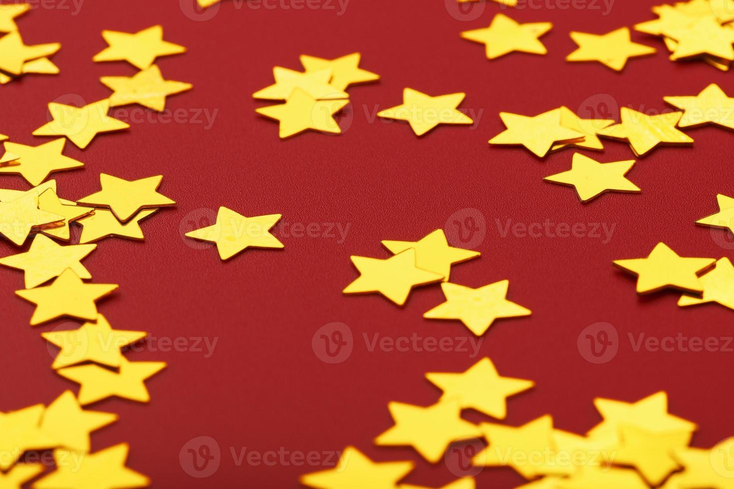 oro stelle su rosso sfondo. il concetto di saluto carte, titoli e ragnatela luogo. un' dispersione di d'oro stelle foto