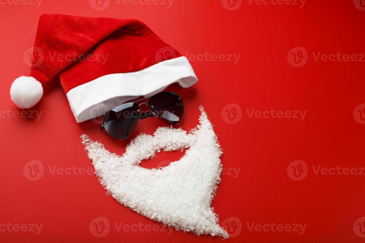 Santa Claus cappello e barba fatto di neve con nero bicchieri su rosso sfondo. foto