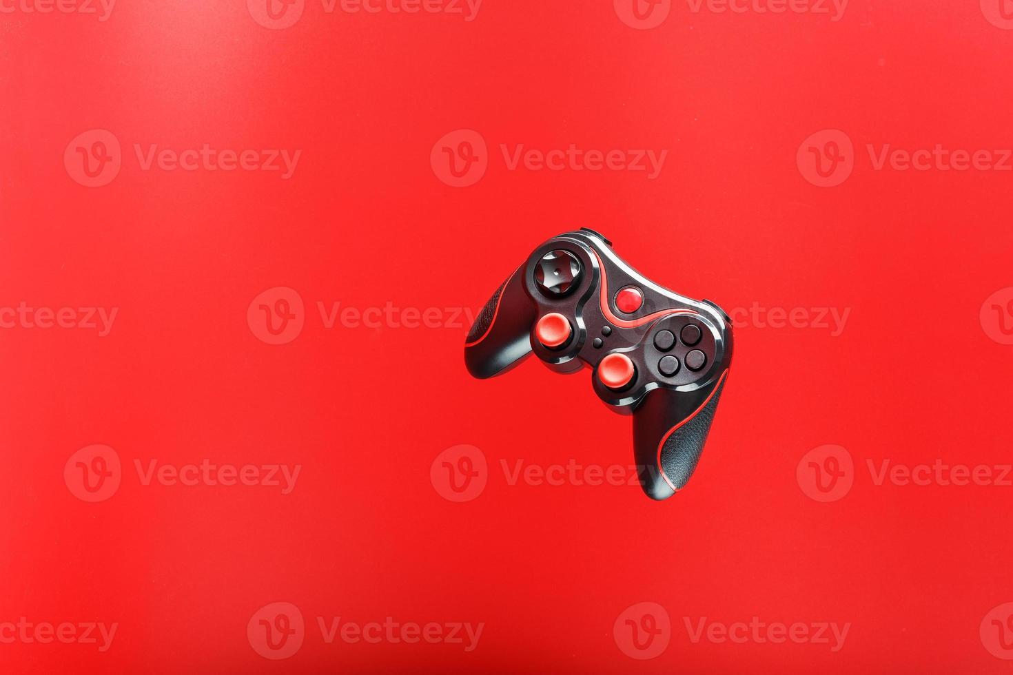 un' nero telecomando da gioco gioco controllore si libra isolato su un' rosso sfondo. interattivo divertimento foto
