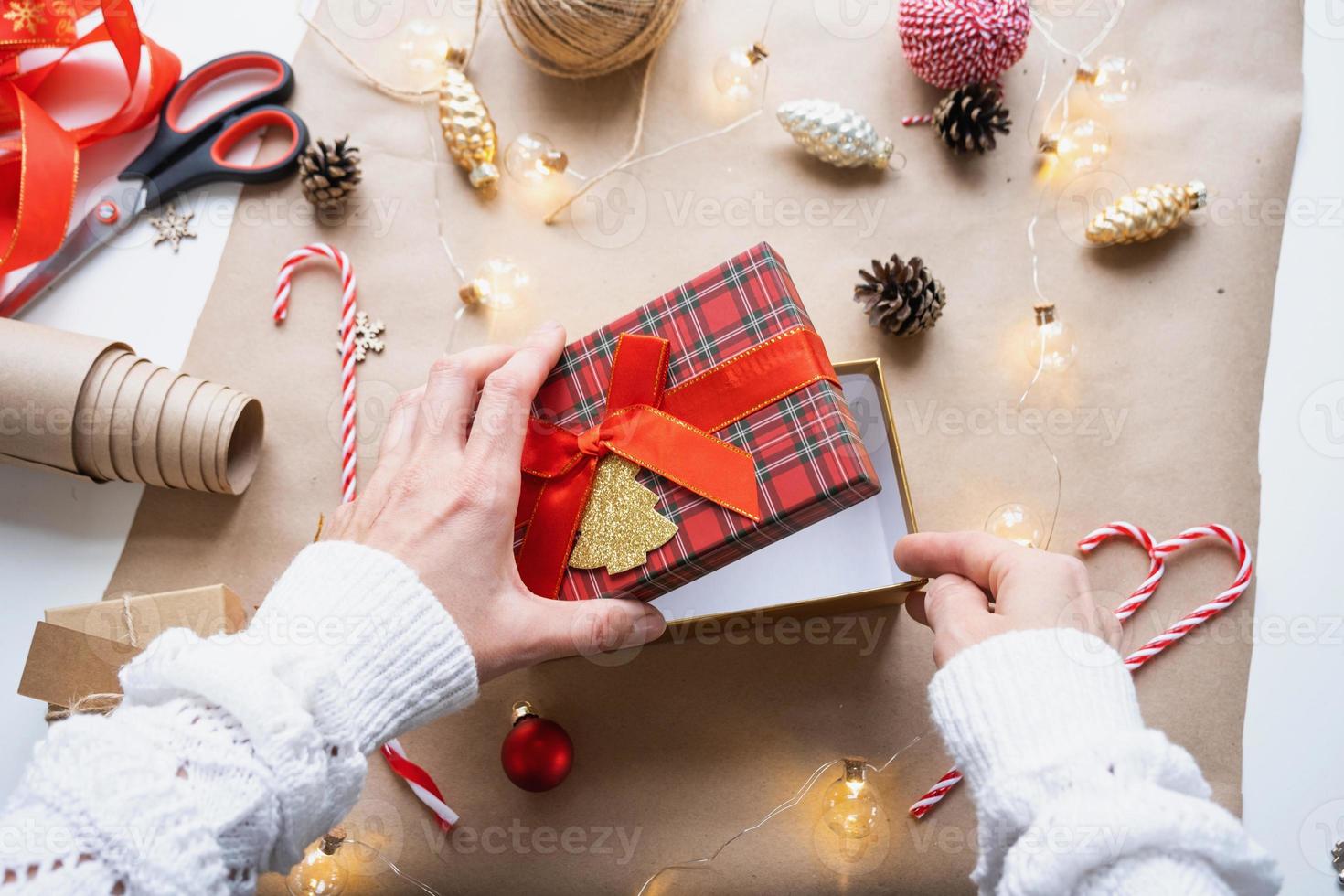 imballare un' regalo per Natale e nuovo anno nel kraft carta, coni, nastro, forbici. tag con finto su, naturale arredamento, mano fatto, Fai da te. festivo umore. piatto, sfondo foto