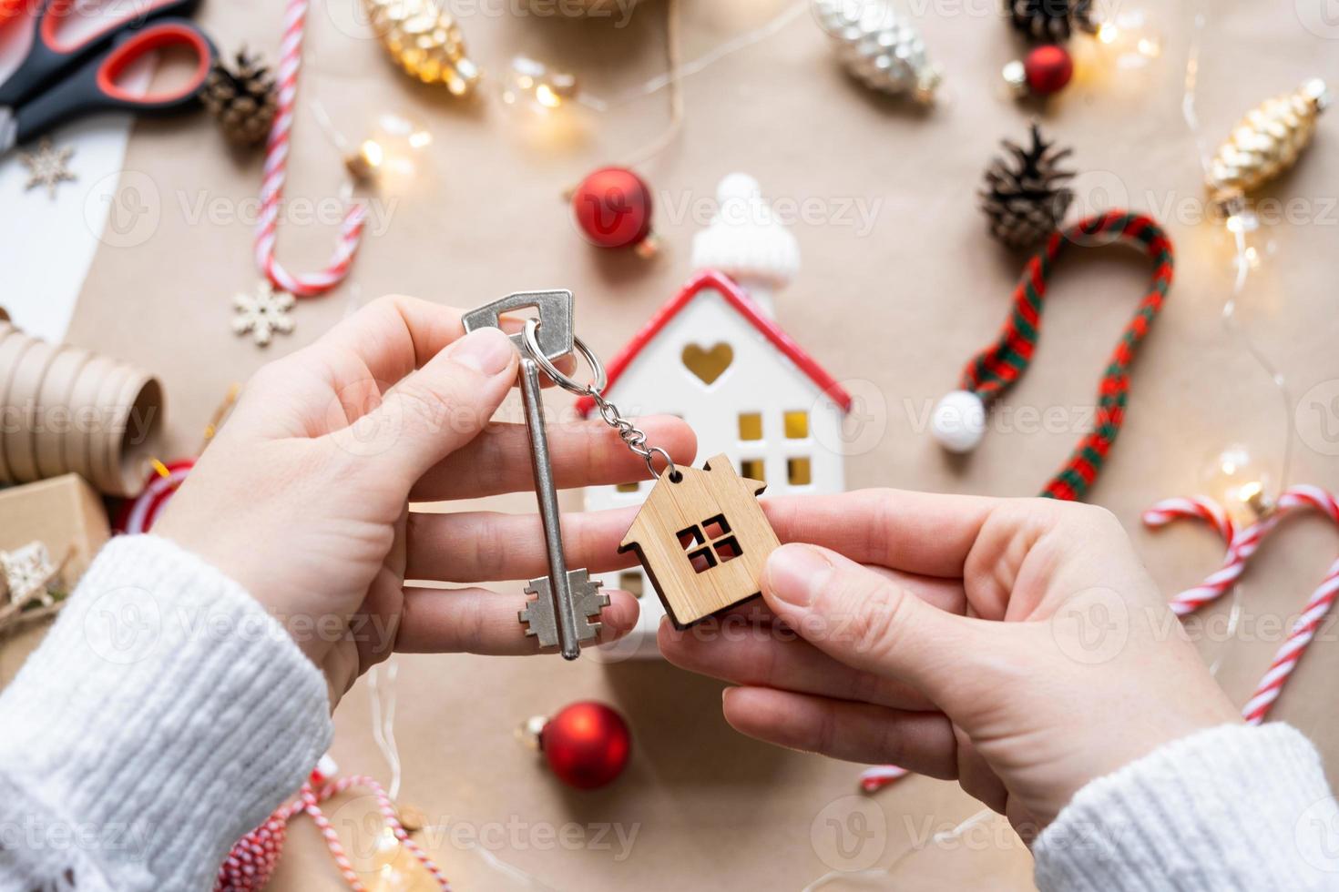 chiave per il Casa con un' portachiavi su un' accogliente casa con un' Natale arredamento disposizione. un' regalo per nuovo anno, Natale. costruzione, disegno, progetto, in movimento per nuovo Casa, mutuo, affitto e Acquista vero tenuta foto