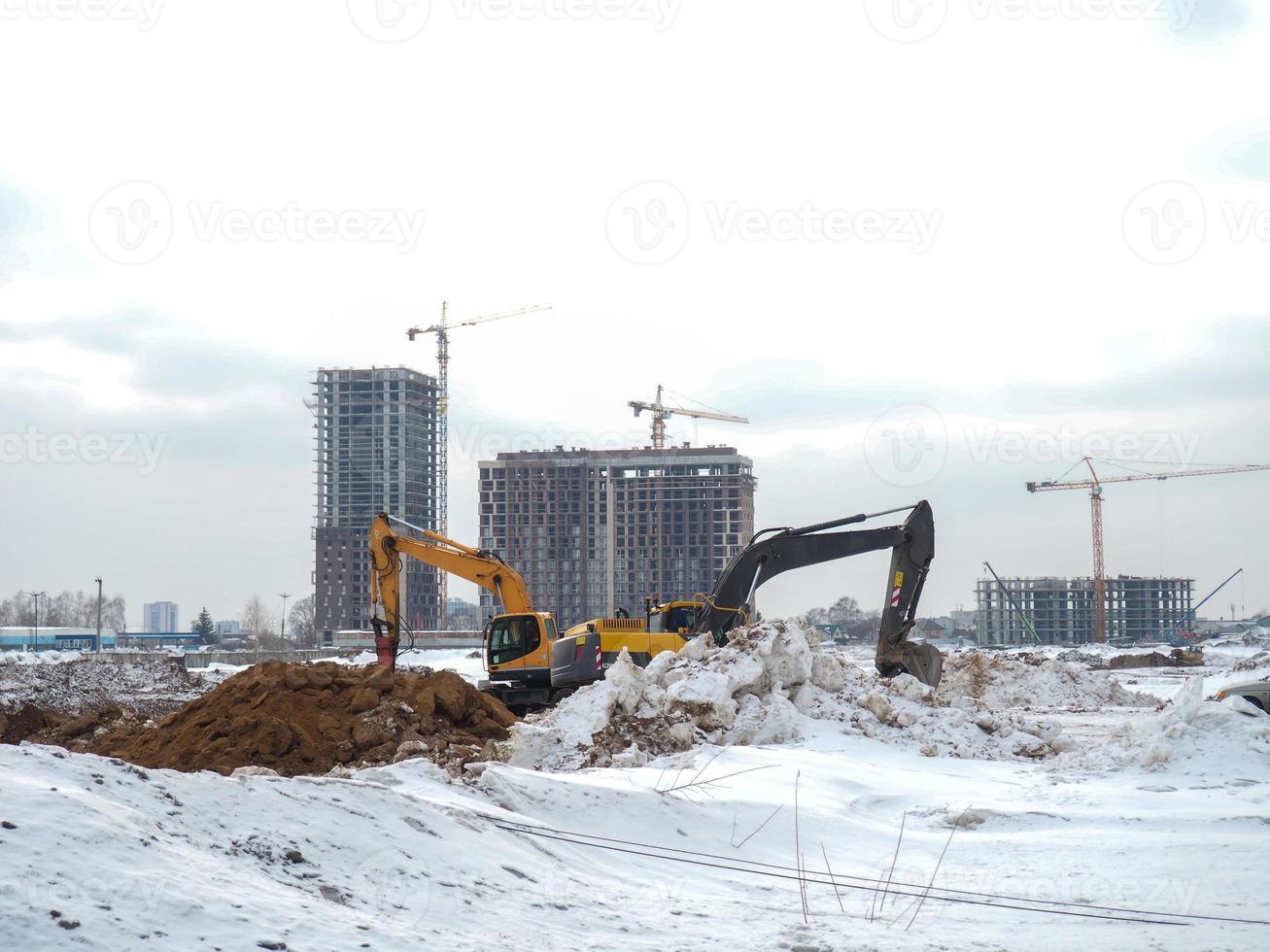 costruzione di grattacielo edifici nel inverno. il opera di escavatori. terra lavori. scavando pozzi. foto