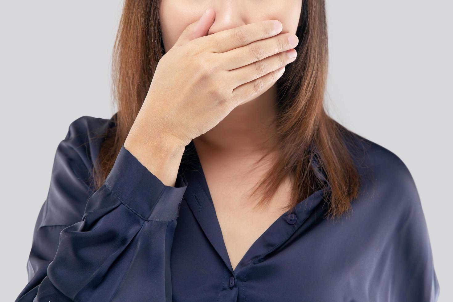 il donna nel un' buio blu camicia non commentando e rifiutando. donna con sua mani su sua bocca perché di cattivo respiro o alitosi foto