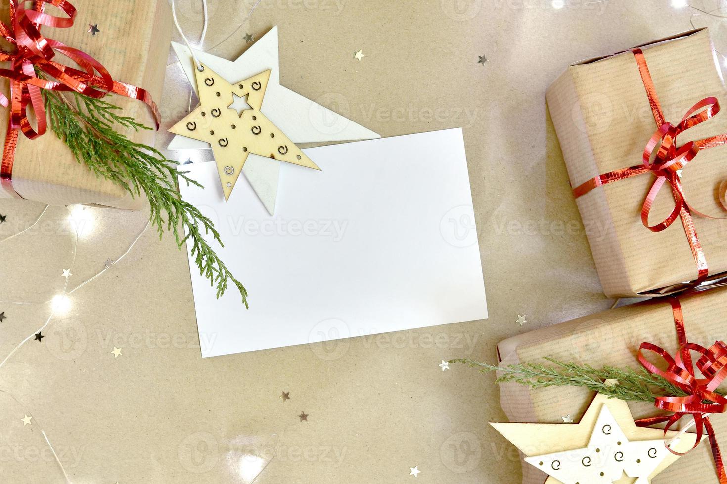 i regali e sparpagliato luccichio stelle su un' beige mestiere carta sfondo con luci e bianca foglio. foto