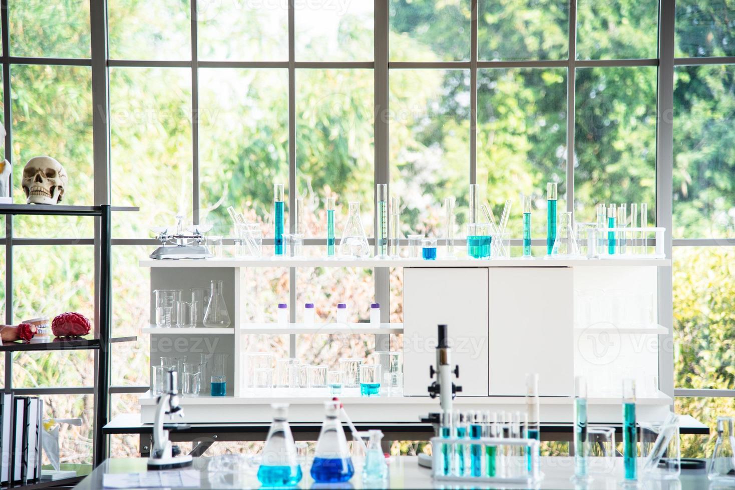 preparazione di attrezzature di laboratorio come vetreria, tubo con liquido blu sul tavolo bianco. l'esperimento di chimica nella ricerca scientifica foto