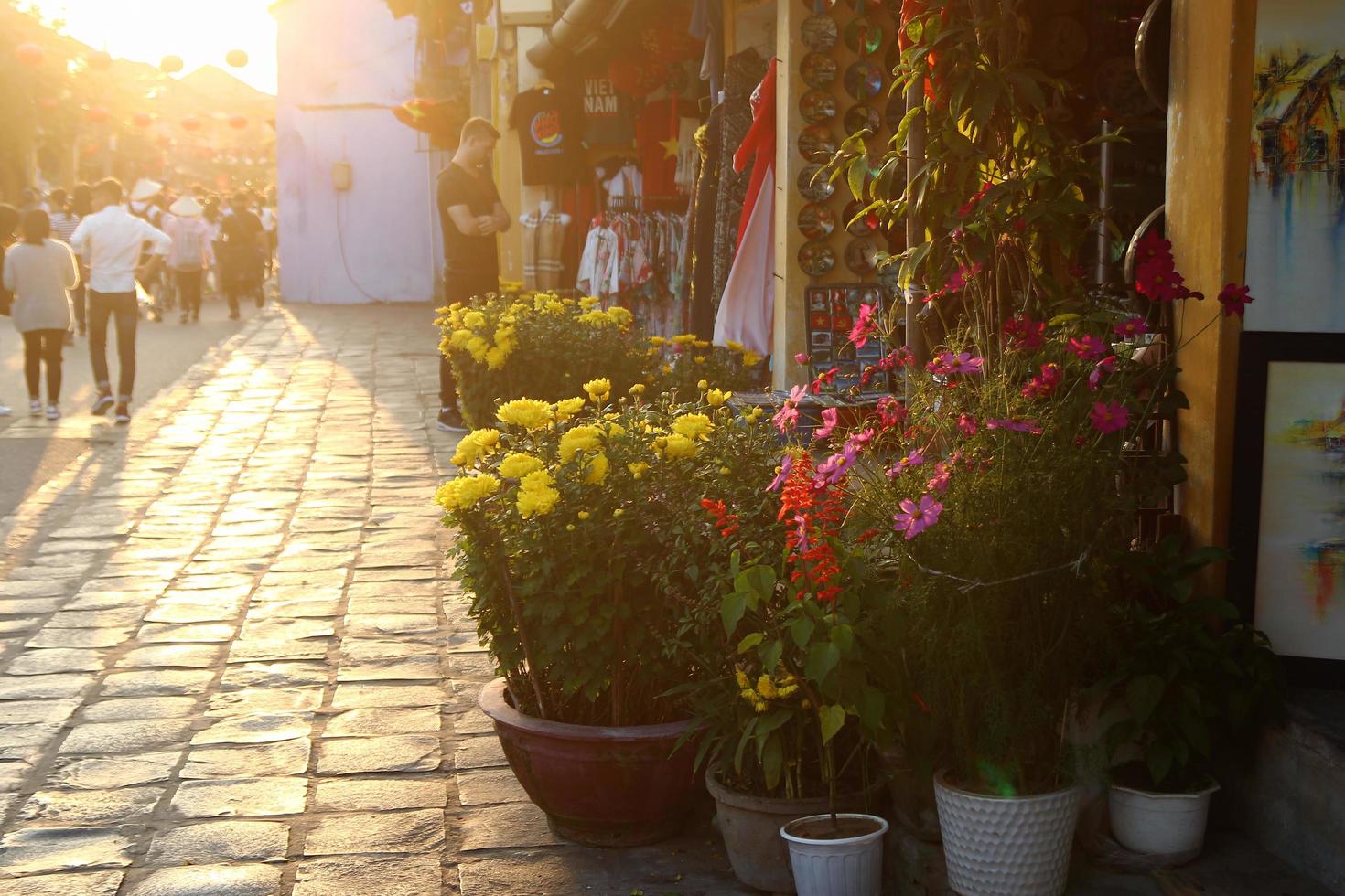 Hoi un, Vietnam - febbraio 17, 2018. turistico strada nel vecchio storico cittadina con negozi, colorato fiori e a piedi turisti a il tramonto. foto