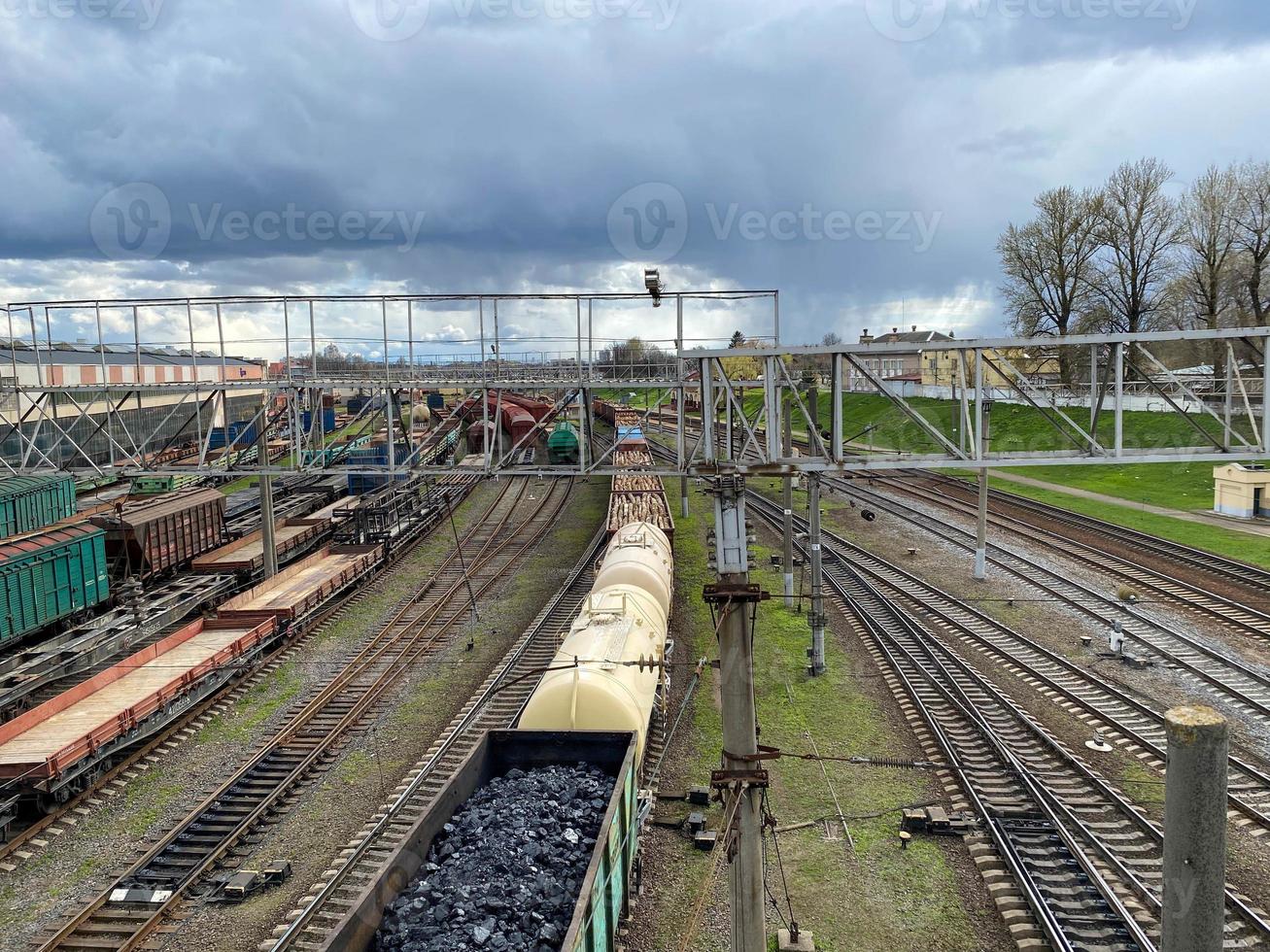 aereo Visualizza di colorato nolo treni su ferrovia stazione. carri con merce su Ferrovia. carico treni. pesante industria. industriale scena con treni, città edifici e blu cielo a tramonto. superiore Visualizza foto