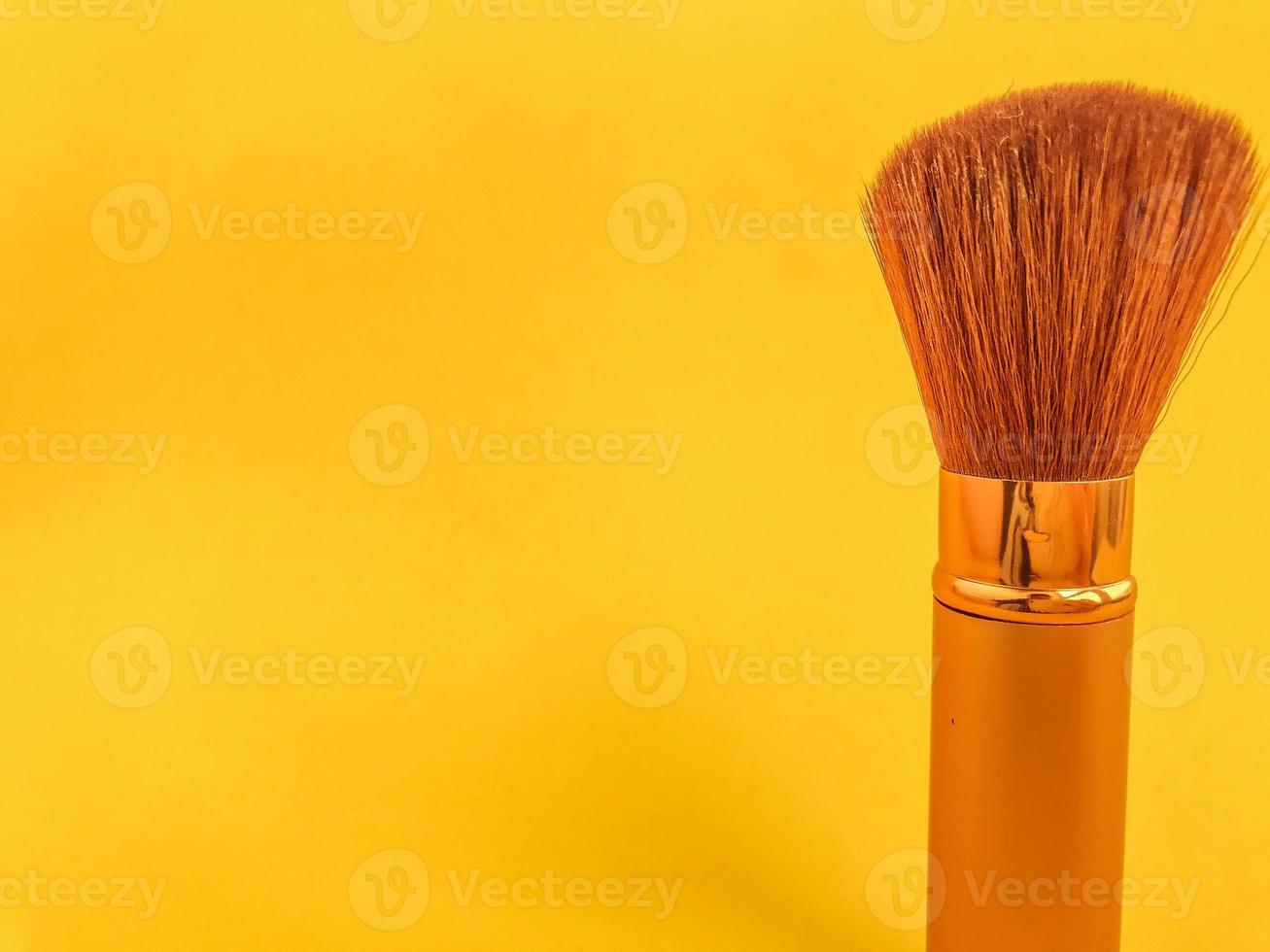 bellissimo alla moda bellezza cosmetico affascinante bianca e oro spazzole e spazzole per l'applicazione trucco e polvere e cosmetici su il viso su un' giallo dolce sfondo. piatto posare foto