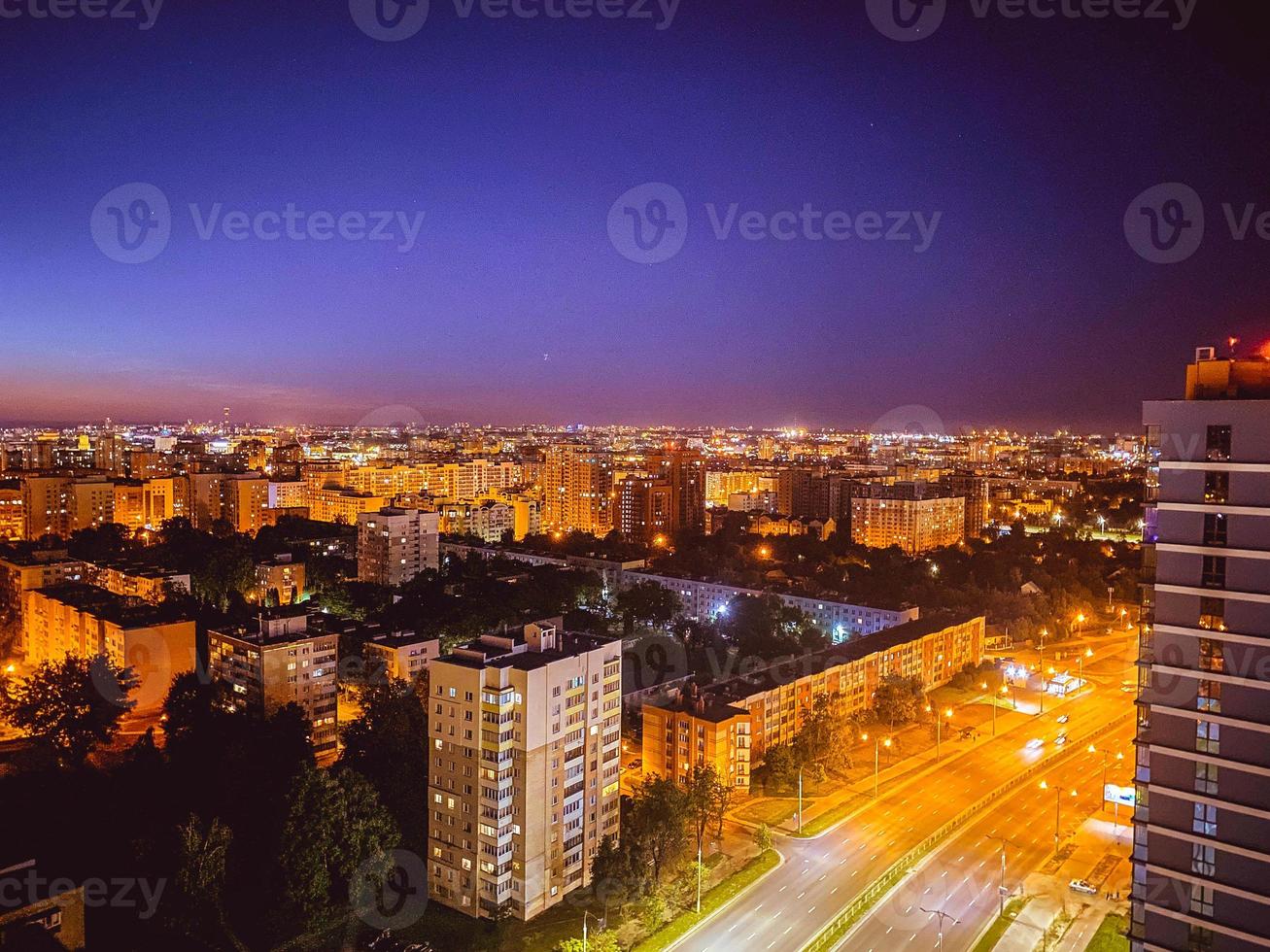 Visualizza di il notte città a partire dal un' altezza. alto case con panoramico finestre e dipinto facciate. bellezza di il circostante mondo. luci su nel il finestre foto