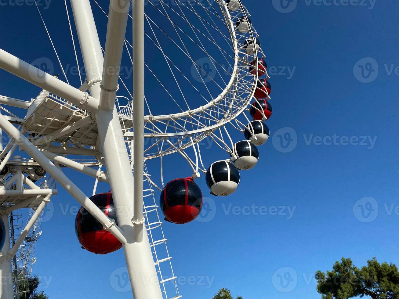 avvicinamento moderno Ferris ruota contro blu cielo e bianca nuvole. Ferris ruota a luna park per divertimento e ricreazione su vacanza. moderno costruzione di Ferris ruota nel divertimento. divertimento Festival foto