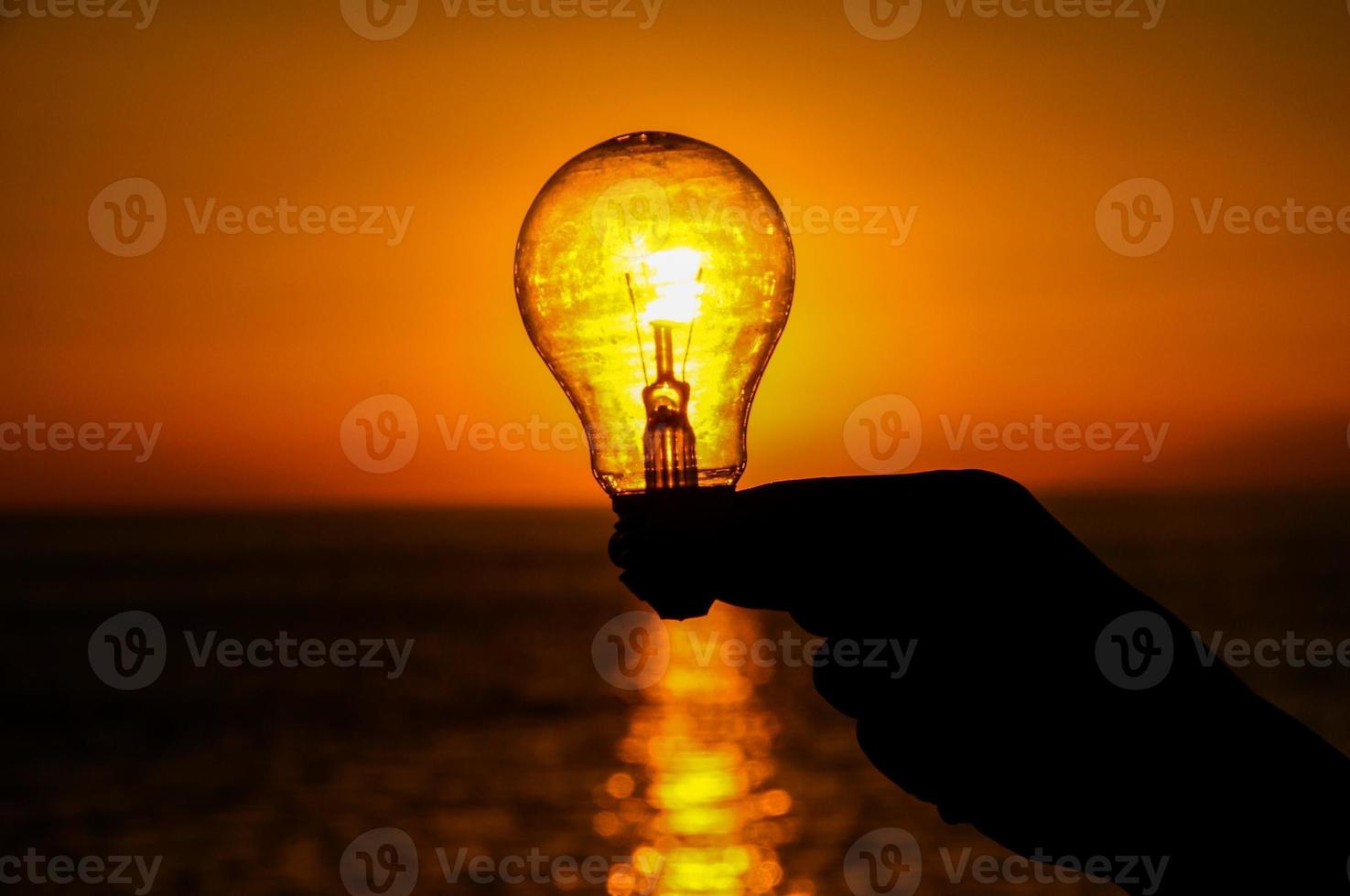 mano Tenere un' lampada di il tramonto foto
