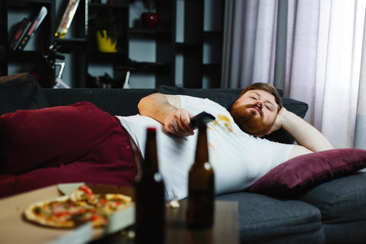 uomo grasso si trova sul divano e guarda la tv foto