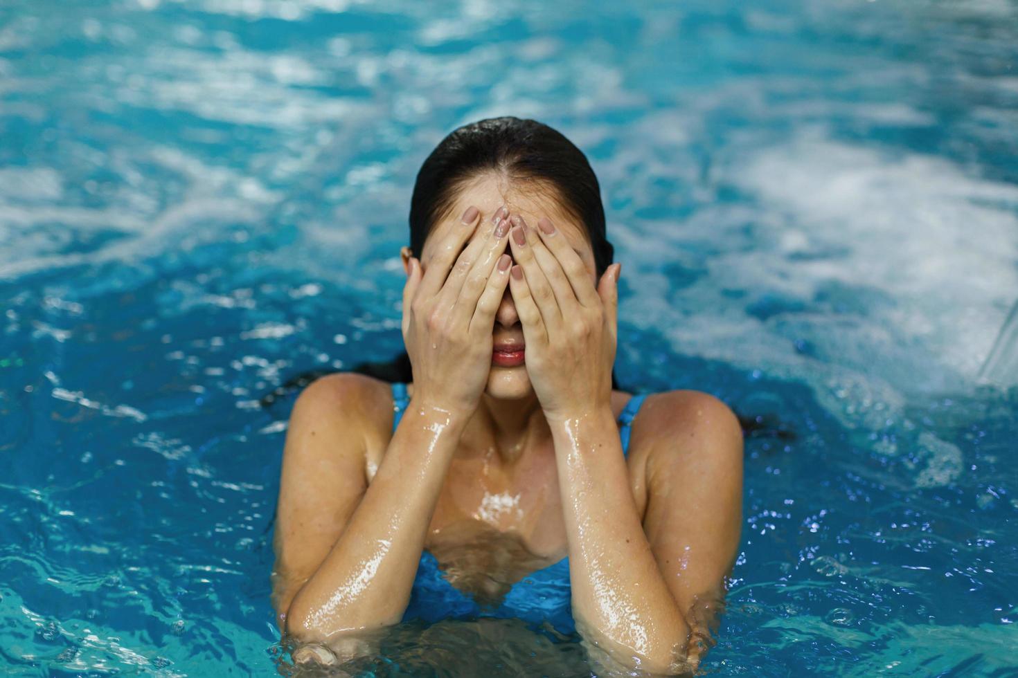 ragazza che copre gli occhi in piscina foto