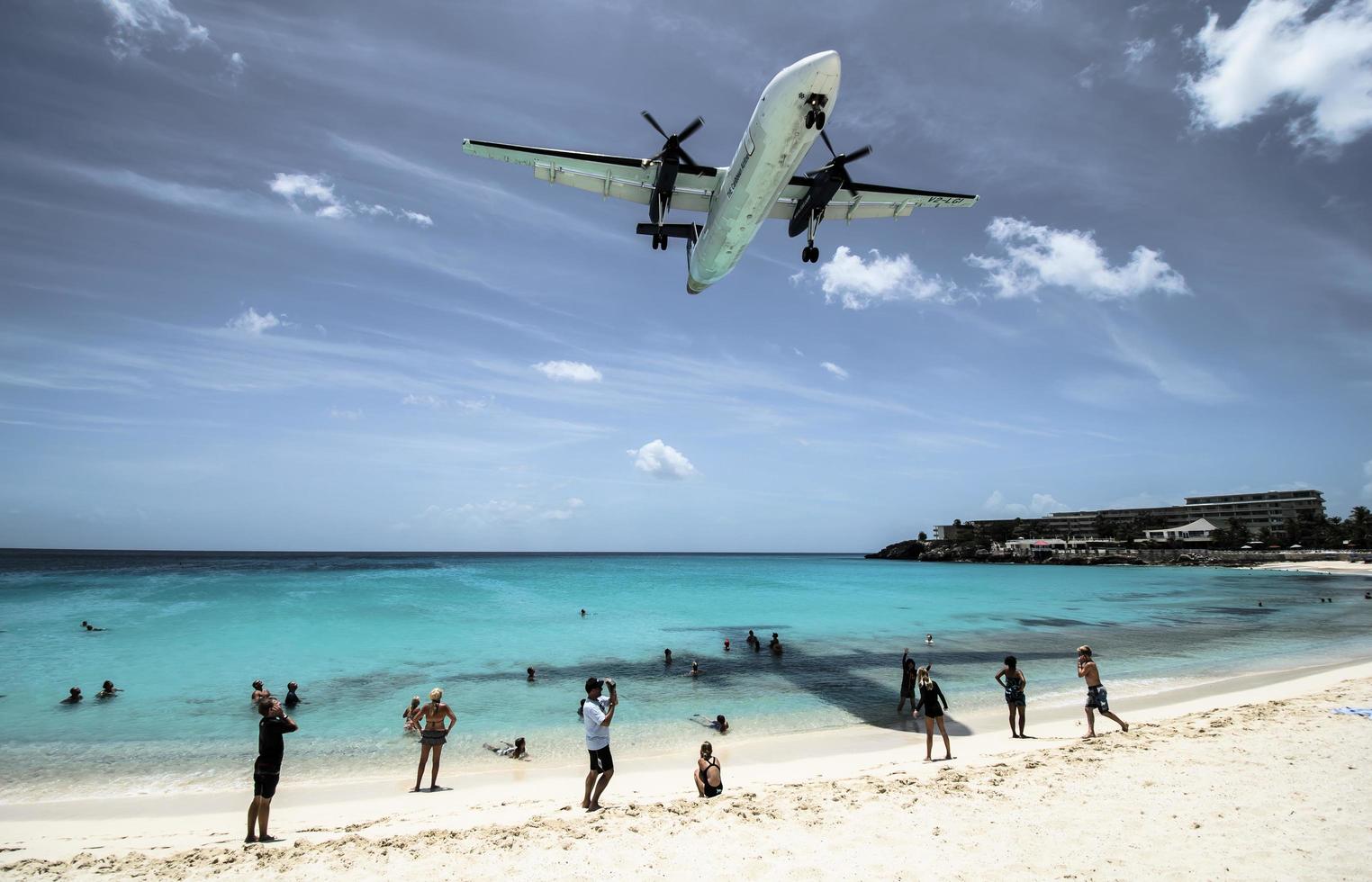 st. Martin, 2013 - i turisti affollano la spiaggia di Maho mentre un aereo a bassa quota si avvicina alla pista sopra il litorale foto