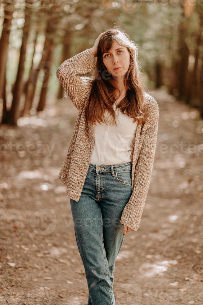 ritratto di un' ragazza con Marrone capelli, nel un' cardigan, su un' camminare nel il foresta. foto