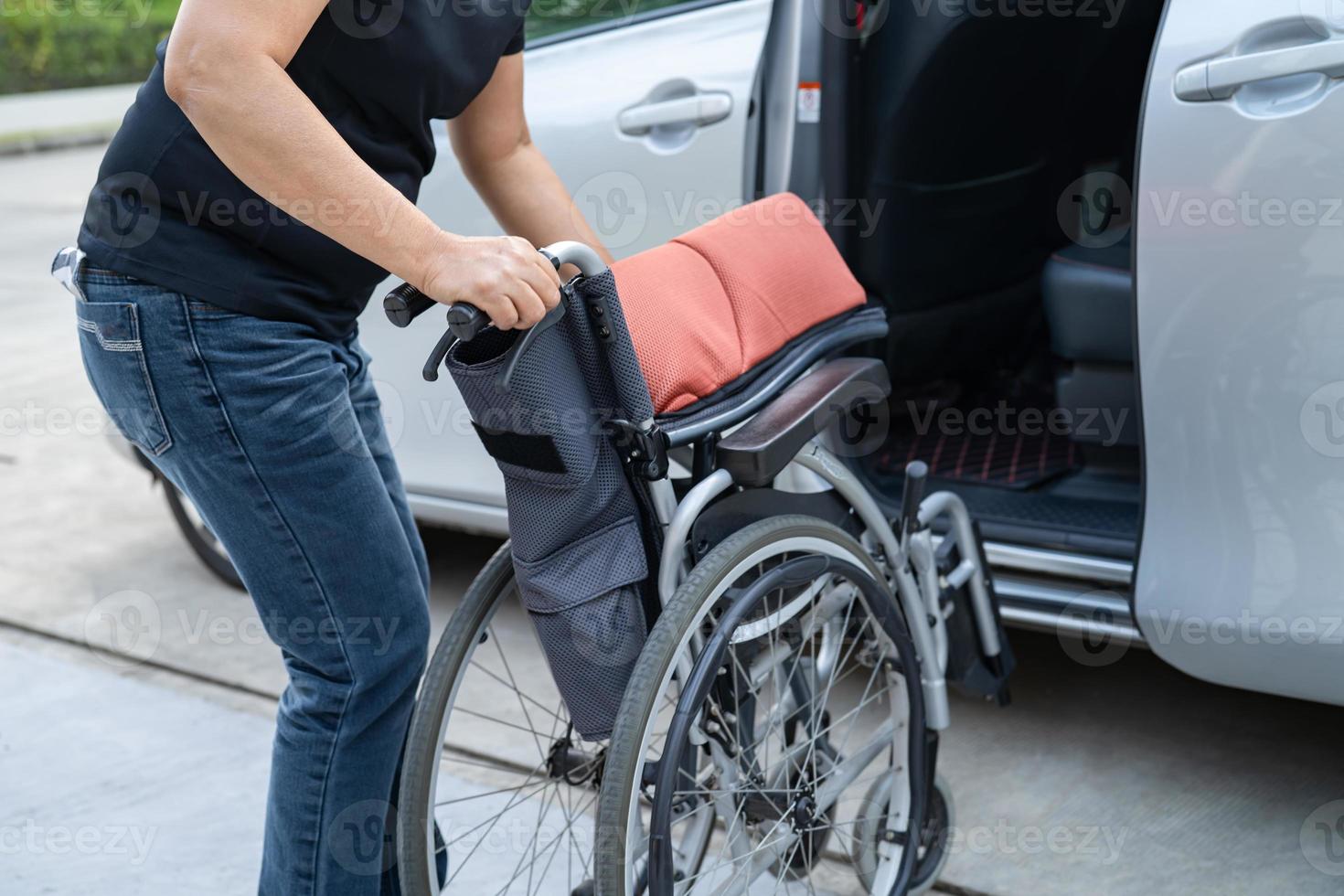 donna asiatica che piega e solleva la sedia a rotelle nella sua auto. concetto di accessibilità. foto