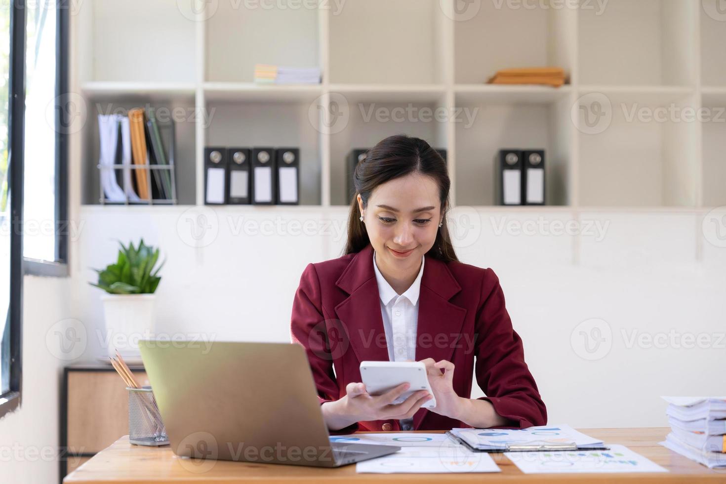 asiatico attività commerciale donna utilizzando calcolatrice e il computer portatile per fare matematica finanza su un ufficio scrivania, imposta, rapporto, contabilità, statistiche, e analitico ricerca concetto foto