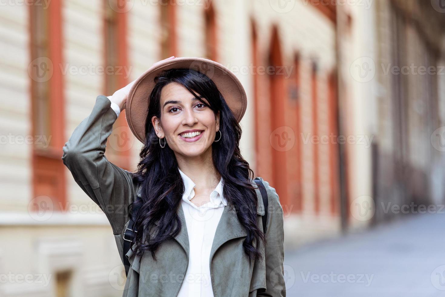 soleggiato stile di vita moda ritratto di giovane elegante fricchettone donna a piedi su il strada, indossare di moda vestito, cappello, viaggio con zaino. foto