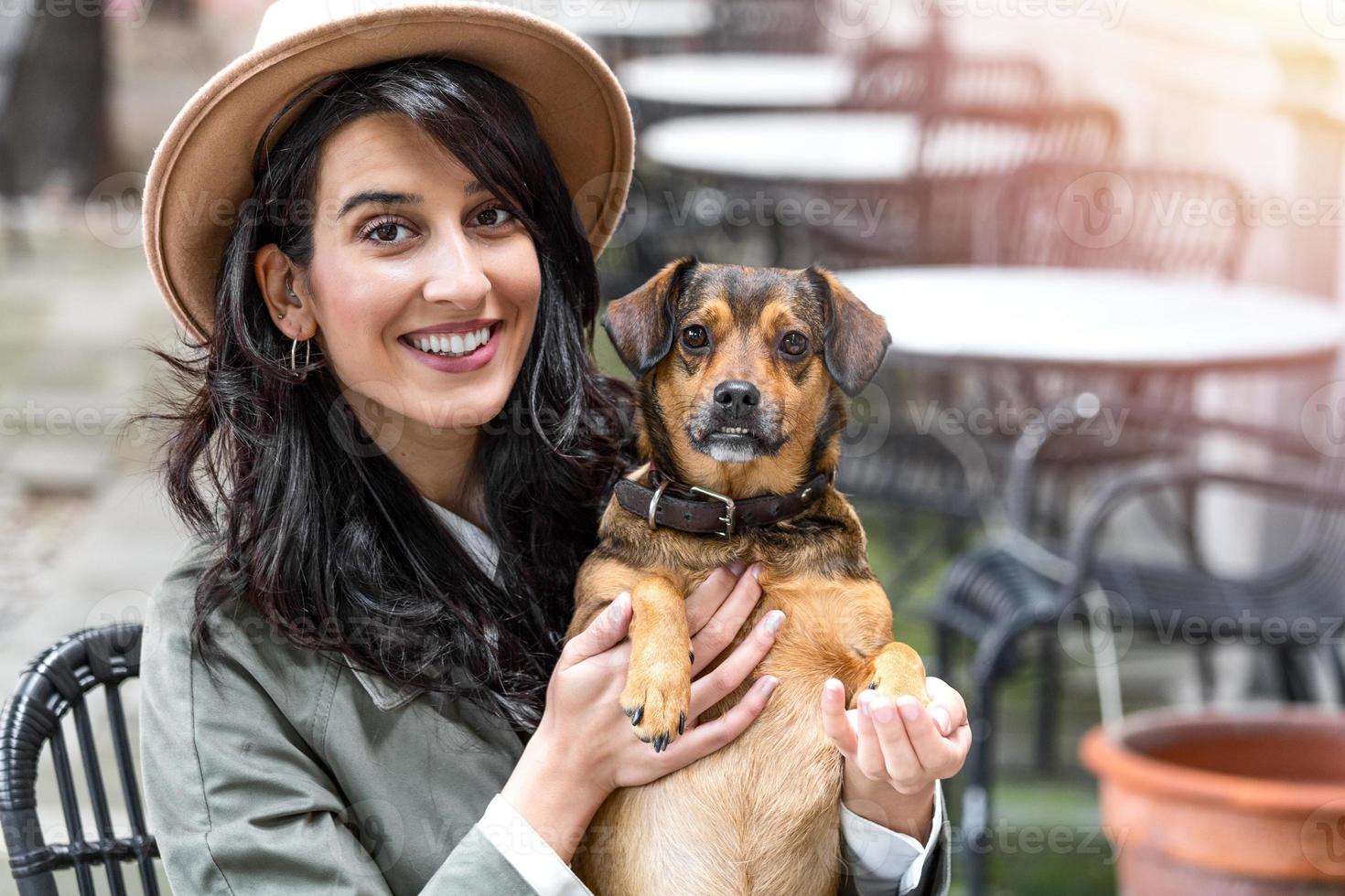 attraente giovane donna seduta nel caffè negozio, rilassante e Tenere sua cane. animale domestico amichevole caffetteria, bellissimo ragazza con sua cane ubicazione a un' caffè negozio e bevanda caffè. foto