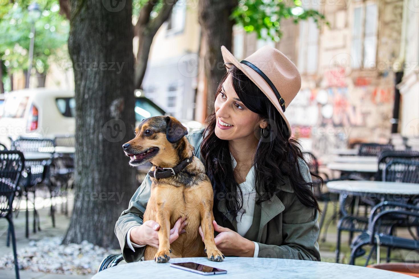 attraente giovane donna seduta nel caffè negozio, rilassante e Tenere sua cane. animale domestico amichevole caffetteria, bellissimo ragazza con sua cane ubicazione a un' caffè negozio e bevanda caffè. foto