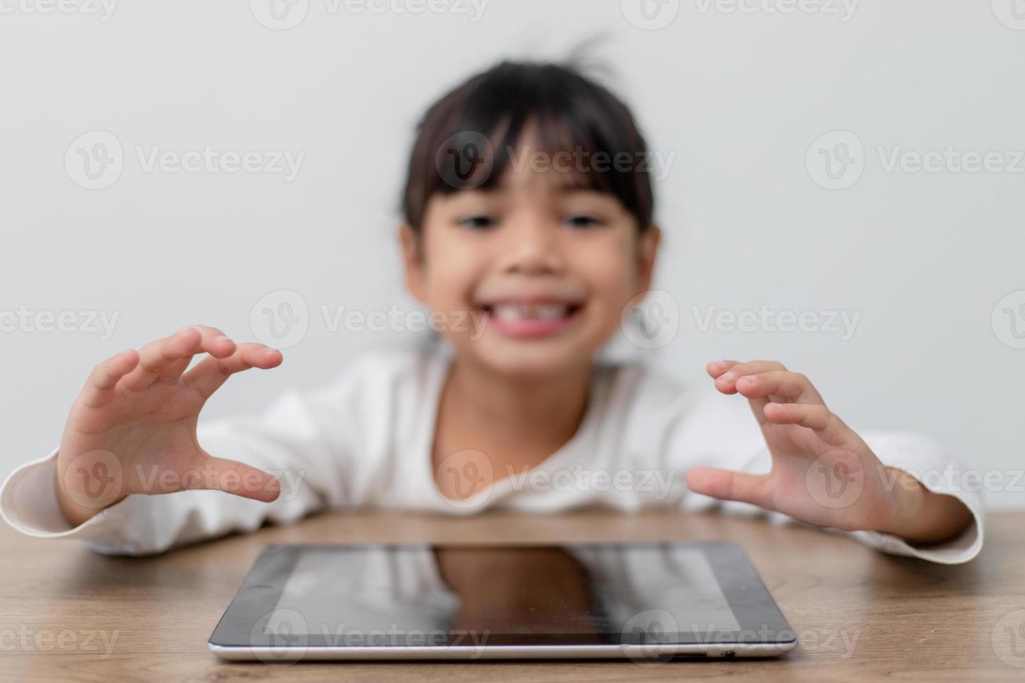 asiatico poco carino ragazza toccante il digitale tavoletta schermo su il tavolo foto